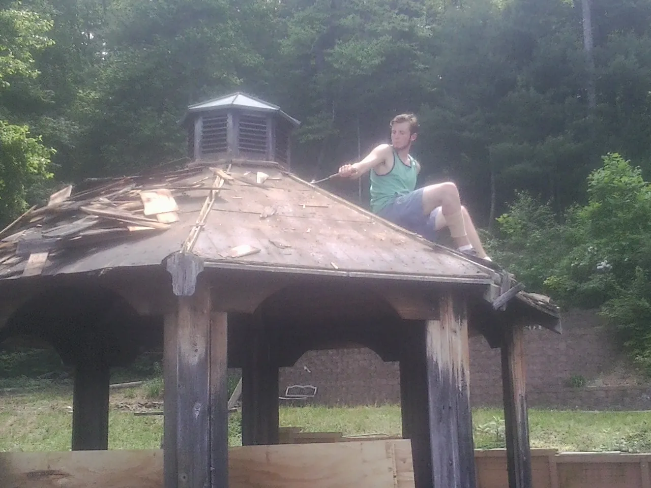 Tearing the old roof off a wooden gazebo before new shakes in Troy