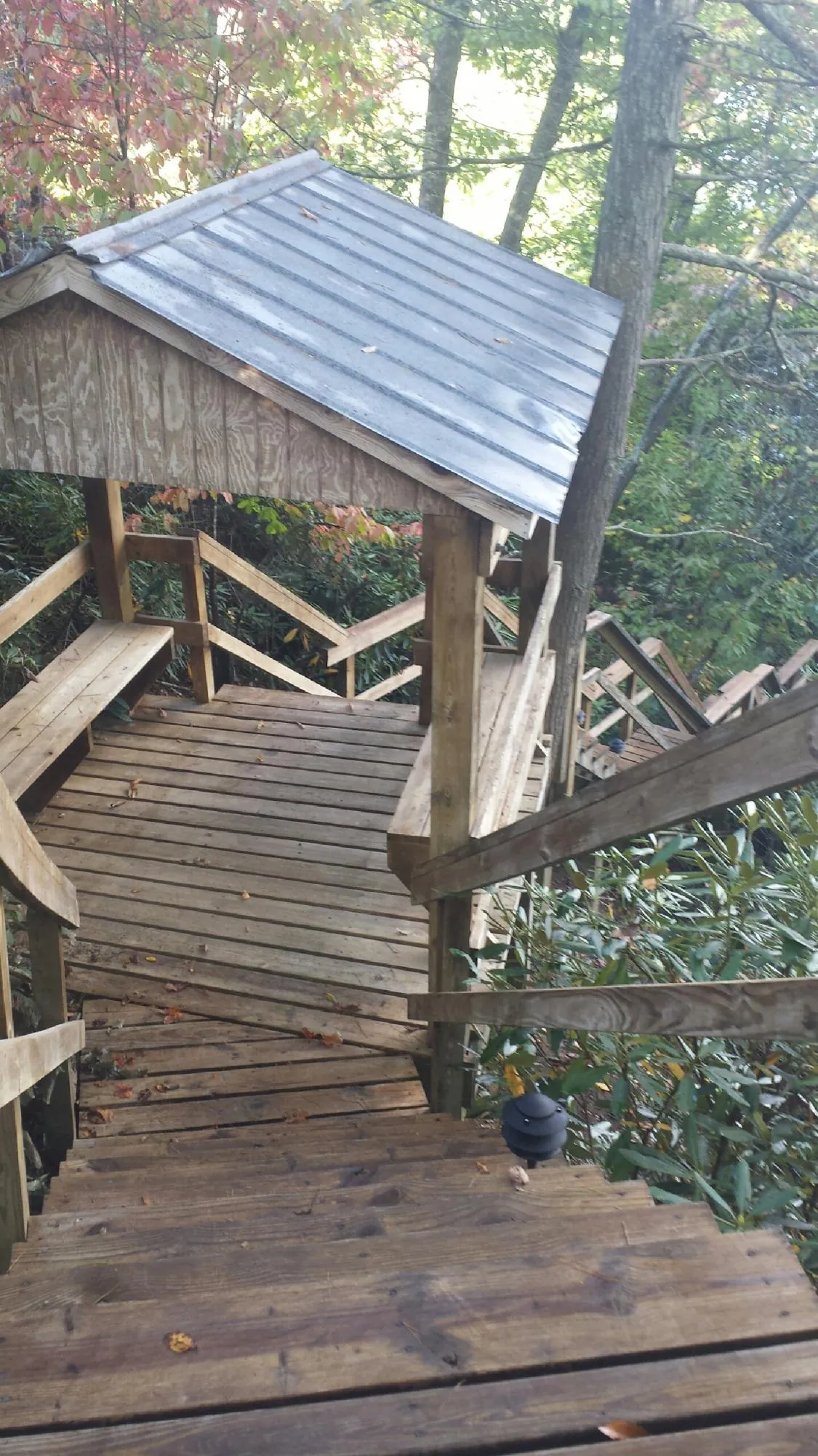 Metal roofed shelter over wooden steps on a wooded walkway — Skylight Repair & Installation work by our crew in Troy